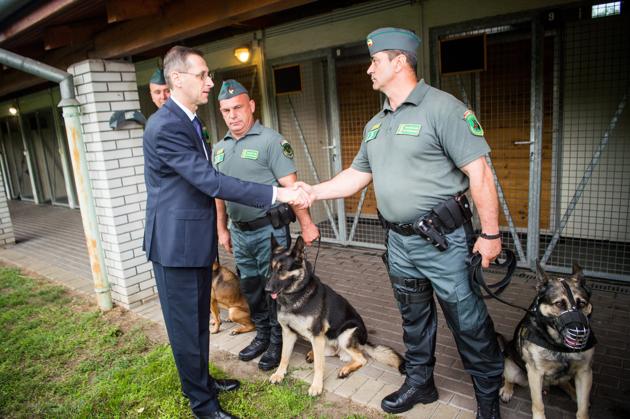 Varga Mihály pénzügyminiszter (b) kezet fog Germán Sándor pénzügyőrrel, mielőtt elismerő okleveleket ad át a kutyakiképzőknek Budapesten a NAV Bevetési Igazgatóságának kutyakiképző központjában