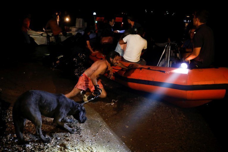 Egy férfi épp a kutyáját próbálja betenni a mentőcsónakba